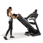 A woman in athletic attire folding the Sole F80 Treadmill