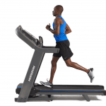 A man in athletic attire running on the Horizon 7.4 AT treadmill