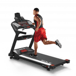 A man in athletic attire running on the Sole TT8 treadmill