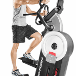 A man in athletic attire working out on the ProForm HIIT Trainer Elliptical