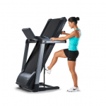 A woman in athletic attire folding the TR3000i treadmill upwards